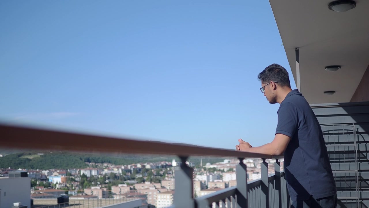 Giovane uomo in piedi sul balcone che ammira il panorama della città