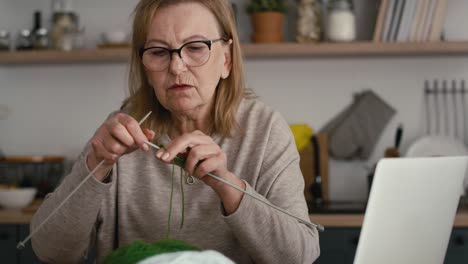 Ältere-Kaukasische-Frau-Zu-Hause-Lernt-Anhand-Eines-Video-Tutorials,-Wie-Man-Strickt