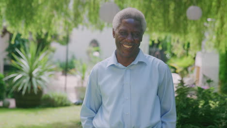 portrait of relaxed senior man standing in garden at home after retirement