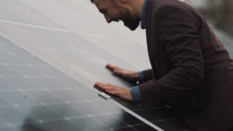 satisfied man in business clothes hugs and kisses solar panel