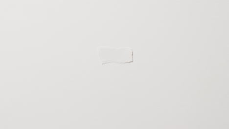 Video-of-close-up-of-torn-piece-of-paper-with-copy-space-on-white-background