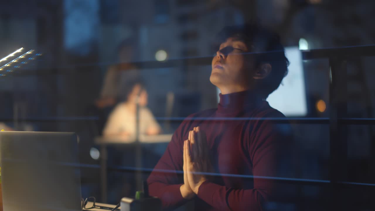 Stressed asian businessman meditating in yoga pose in night office.