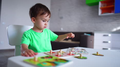 lovely child playing with puzzles at desk. focused toddler is busy with game at home. blurred backdrop.