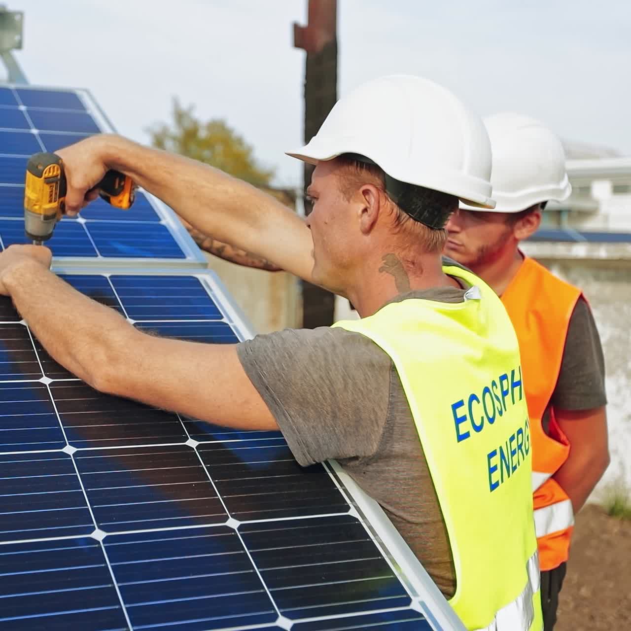 Workers installing photovoltaic solar panels. Men in white helmets installing sunny batteries. Renewable source of energy.