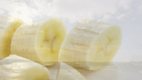 animation of sliced banana pieces floating over serene landscape with cloudy sky