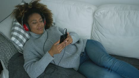 young woman chilling on sofa with gadgets