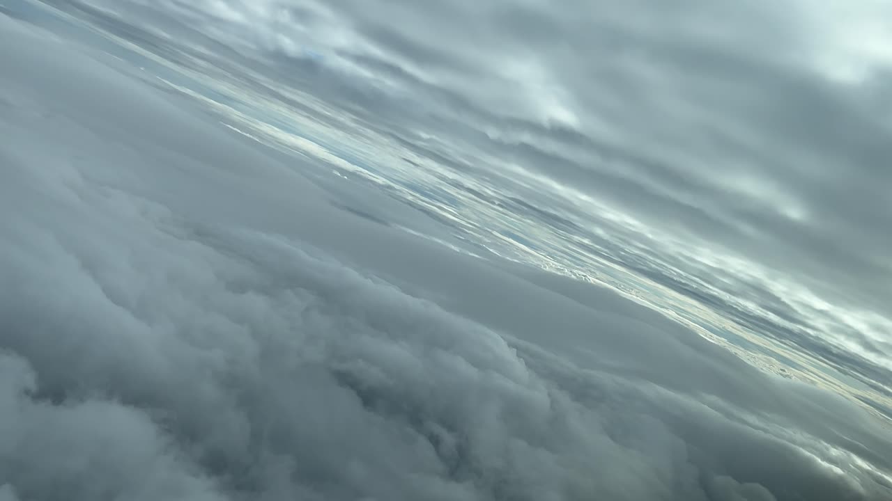 Ripresa aerea POV di un paesaggio nuvoloso dalla cabina di un aereo che vola attraverso strati di nuvole virando a sinistra