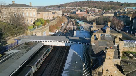 cinematic aerial drone footage of train parked in train station with passengers leaving the train with platform and carpark uk