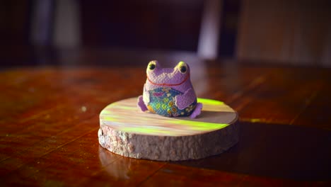 material of the frog : fabric. purple frog doll fabric cloth sitting and smiling on a wooden table
