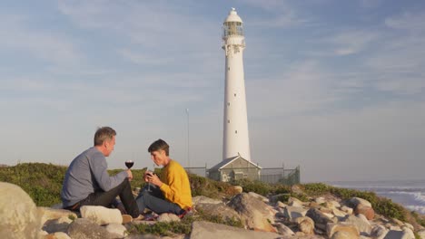 couple drinking wine by the sea near a lighthouse