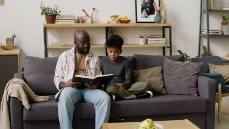 man and boy reading in the sofa