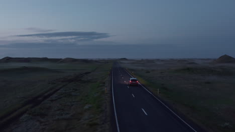 Vista-Aérea-De-La-Carretera-De-Circunvalación-En-Islandia-Con-Un-Coche-De-Conducción-Rápida-Al-Atardecer.-Vista-Superior-Desde-El-Dron-Del-Camión-De-La-Carretera-Conduciendo-Pacíficamente-Al-Atardecer