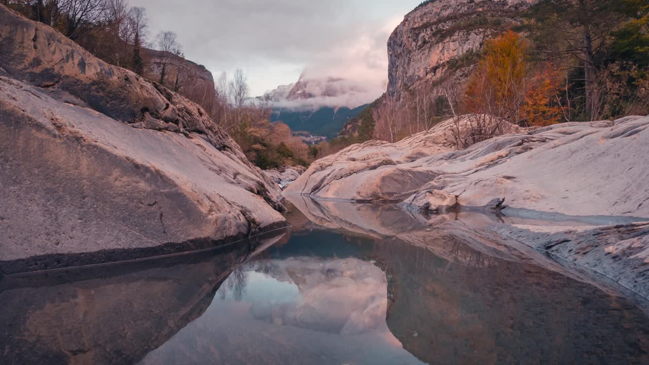 Small lake reflection in Ordesa National park Mondarruego mountain catching last sunrays during sunset timelapse in fall autumn season