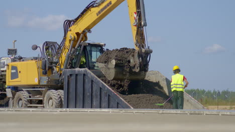 heavy digger lifting full bucket of material from special container