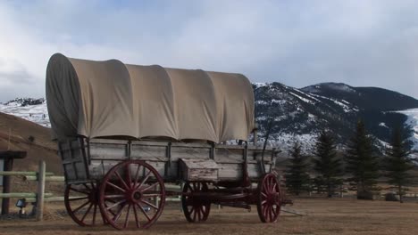 a covered wagon is featured front and center with snowdusted mountains in the background