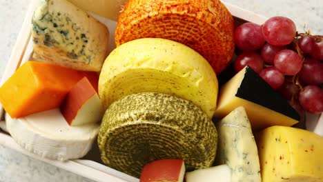 fresh and delicious different kinds of cheeses placed in wooden crate with grapes