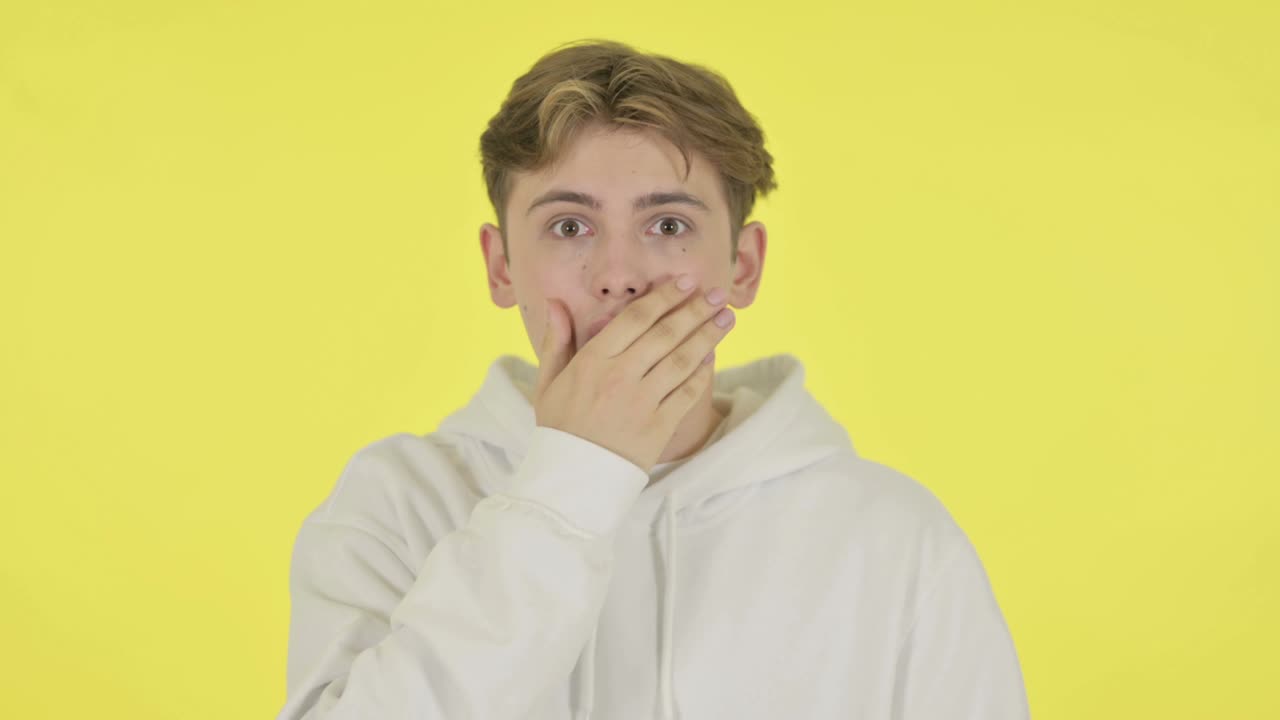 노란색 배경에 충격을 받은 젊은이