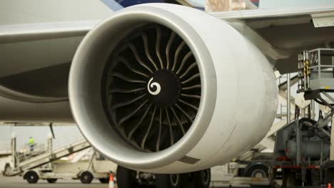 Close-up-view-of-a-large-jet-engine-at-an-airport-with-equipment-in-the-background