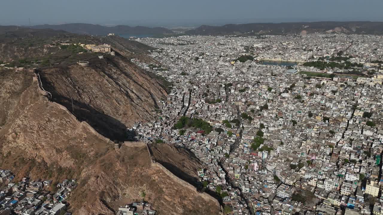 High-altitude shot capturing the dramatic contrast between the rugged hills and dense cityscape.