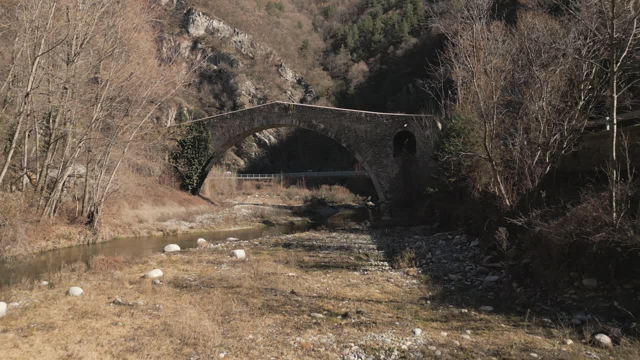 영화 중세 돌 다리 희미한 초록색 건조한 가을 풍경, ribes de freser, girona, 스페인의 pont de la cabreta, 공중 전망, 낮게 날아가는 드론
