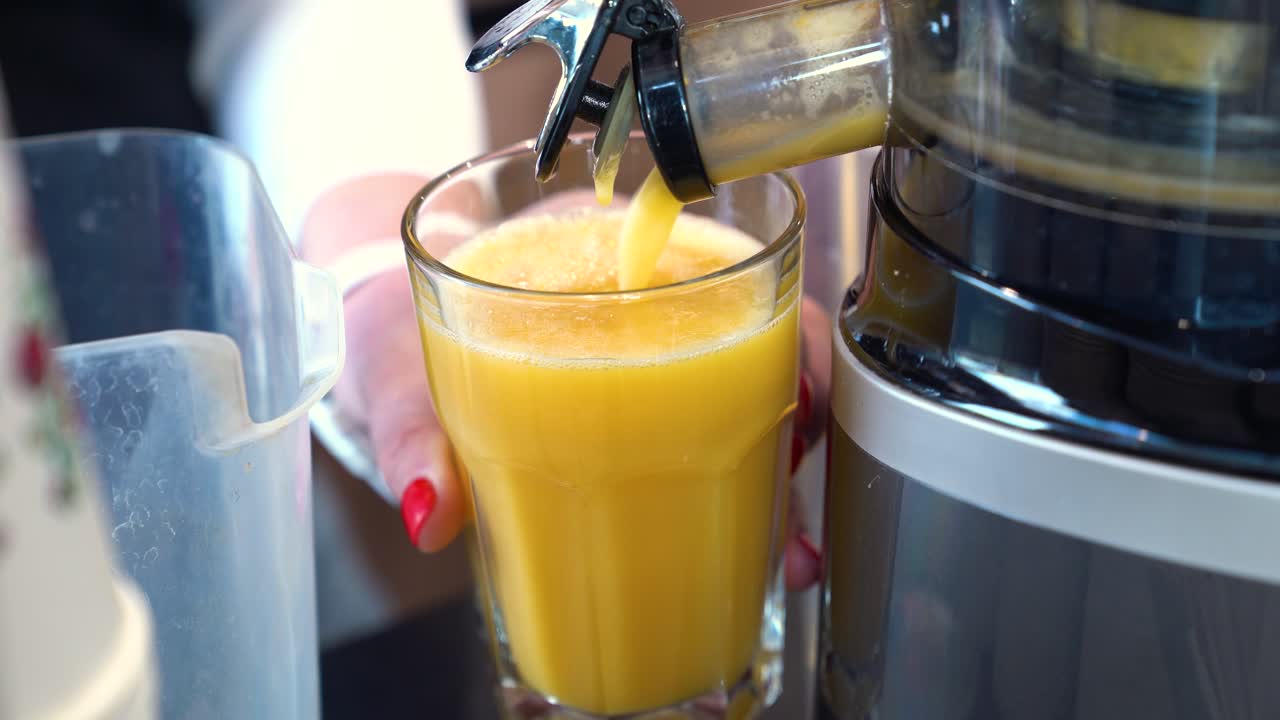 Person Filling Up Glass With Freshly Made Orange And Pineapple Juice. - closeup shot