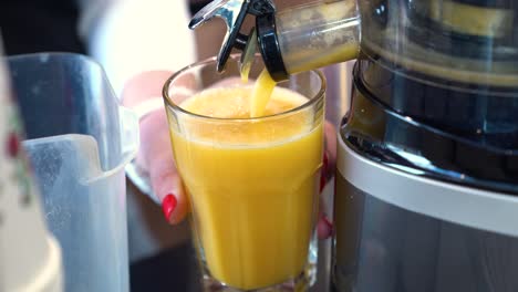 person filling up glass with freshly made orange and pineapple juice. - closeup shot