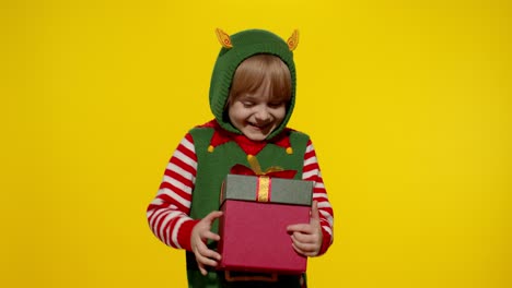 Kid-girl-in-Christmas-elf-Santa-helper-costume-getting,-receiving-present-gift-box.-New-Year-holiday