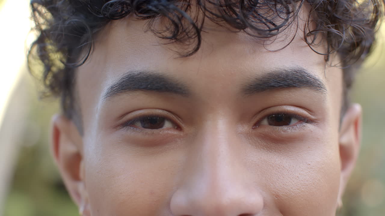 Smiling young man with curly hair looking directly at camera