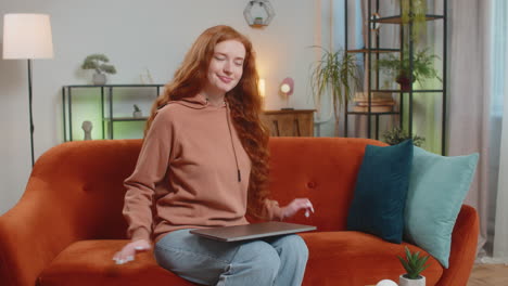 happy caucasian woman sitting on couch closing laptop after finishing work in living room at home