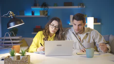 Married-couple-working-together-in-home-office,-attending-video-conference-meeting-together.