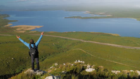 Jubelnder-Mann,-Der-Am-Rand-Einer-Klippe-Steht,-Mit-Blick-Auf-Die-Lagune,-Malerische-Aussicht