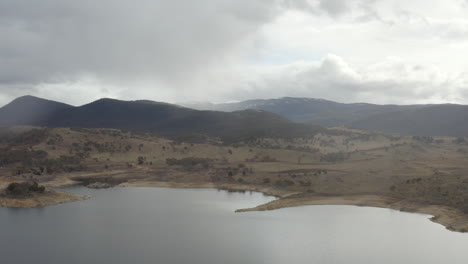 Drone-flying-over-Lake-Jindabyne-towards-the-Kosciuszko-mountain-range-in-the-distance-during-an-overcast-winters-day