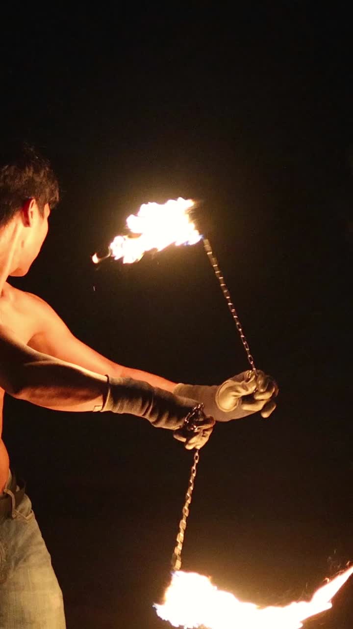 Artista a torso nudo che fa roteare il fuoco di notte