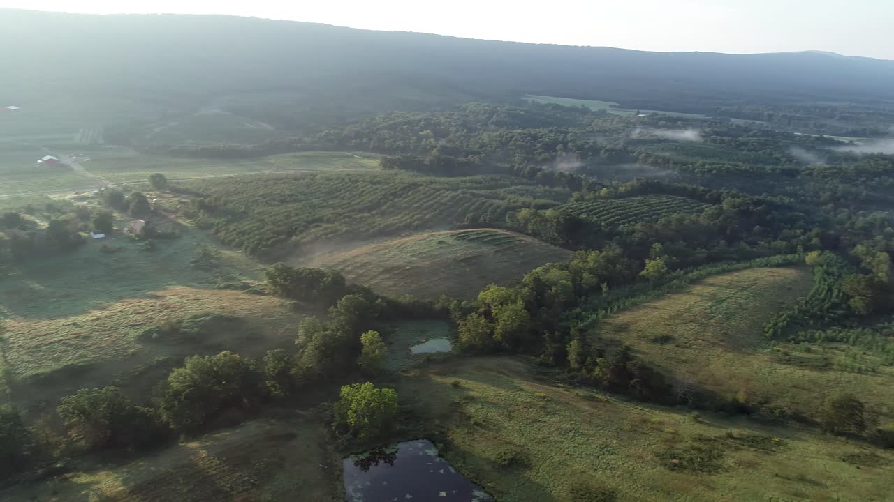 Aerial view of a scenic landscape with mountains, forest, and fields
