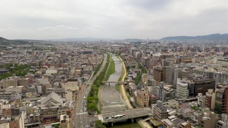 Aerial-of-Kyoto-with-Kamo-river,-temples,-mountains,-and-city-skyline-in-Kyoto,-Japan