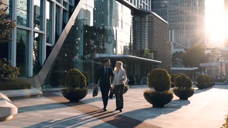 business people walking and talking in front of modern office building