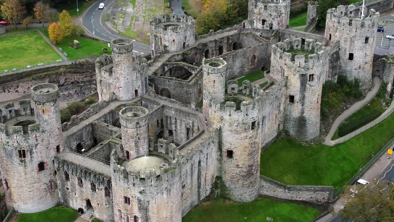 Veduta aerea dello storico Castello di Conwy, un punto di riferimento iconico e attrazione turistica con mura in pietra e merlature, ripreso con un'inquadratura a volo d'uccello ascendente.