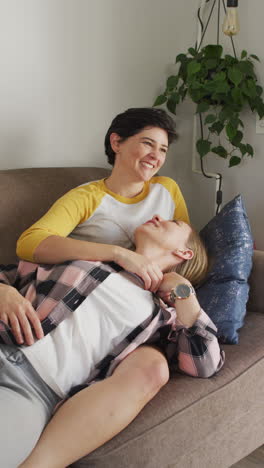 video vertical de una feliz pareja de lesbianas caucásicas abrazándose en casa