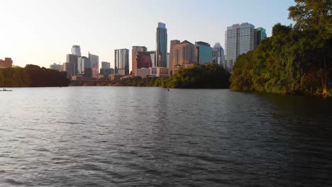 low drone shot of a kayaker paddling towards downtown austin texas