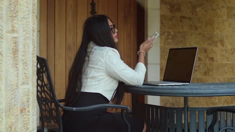 a woman in business clothes engrossed in her laptop at an open-air office.