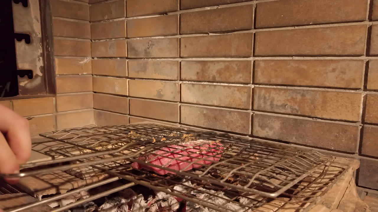 toma en cámara lenta del hombre volteando bistec en barbacoa de carbón por la noche - agregando más condimentos