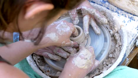 potter's hands work with clay on a potter's wheel