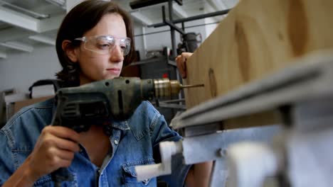 soldadora usando una máquina de perforación en una tabla de madera 4k