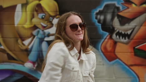 young lady is listening music in front of graffiti