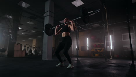 slow motion: a woman lifts a barbell in a dark gym with a lot of weight. a strong young woman lifts weights for a workout