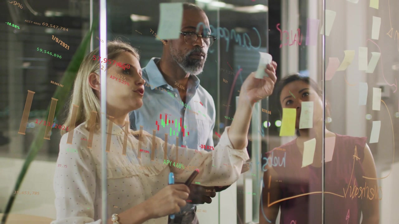Team working at glass, leader peeling sticky note and arranging business plan while charts showing