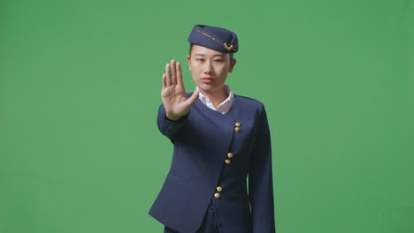 asian woman air hostess looking at camera and disapproving with no hand sign in the green screen background studio