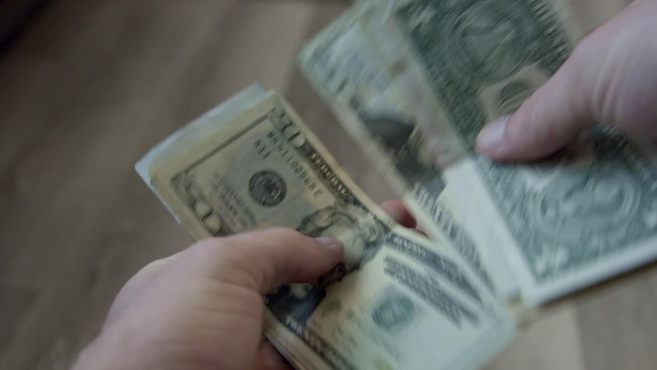 Tæller penge. Håndoptælling af kontanter, udfoldede amerikanske dollarsedler, der tælles i hånden.