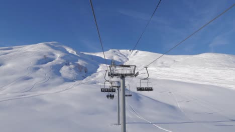 paseo en telesilla que va bastante rápido en las montañas con un clima soleado y un cielo azul claro