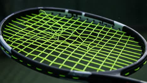 a close-up of a tennis racket with striking green strings highlighting the impact and tension during gameplay, capturing the essence of athletic performance and precision